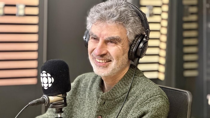 Yoshua Bengio assis devant un micro dans un workplace  de Radio-Canada.