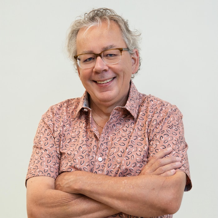 Un homme souriant qui pose les bras croisés.