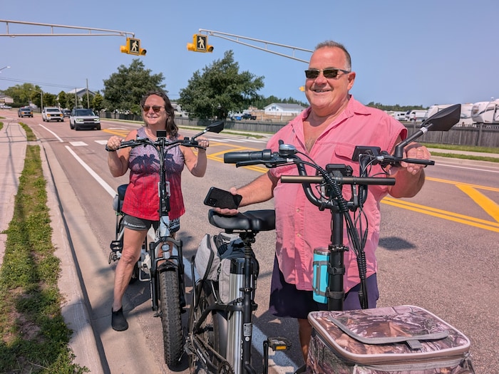 Deux personnes tiennent leurs vélos électriques sur la rue Principale à Shediac.