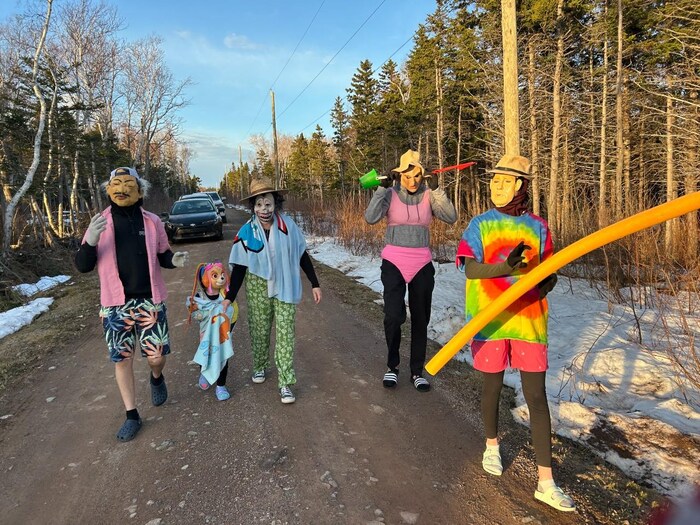Quatre adultes et un enfants costumés marchent dans un sentier.