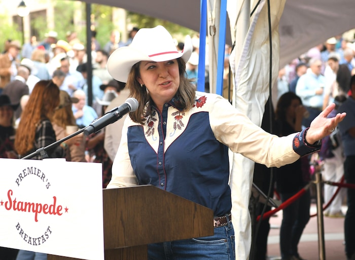 Danielle Smith vêtue d'un chapeau de cowboy blanc, une chemise blanche et bleu marin parlant au podium. 10 juillet 2023.