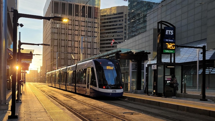 Lever de soleil doré reflétant sur le train entre deux rangées de hauts bâtiments, le 5 avril 2024.