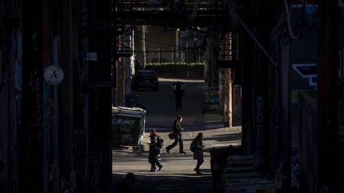 Des gens se promènent dans une ruelle du quartier DTES à Vancouver le 24 janvier 2025.