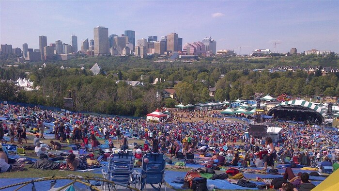 Des festivaliers dans un parc devant des scènes, avec vue sur le centre-ville. (Photo d'archives)