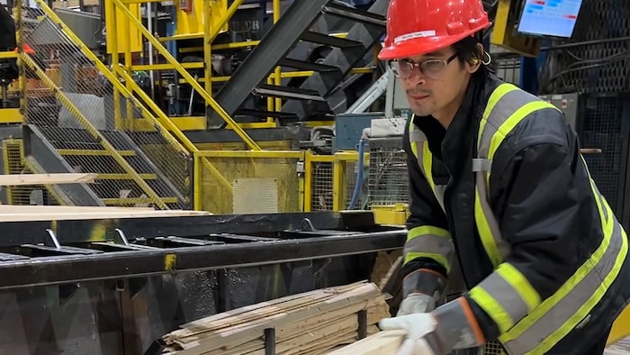 Un employé d'usine place des planches de bois.