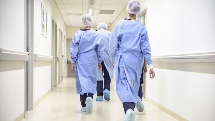 Des infirmiers marchent dans un corridor. 
