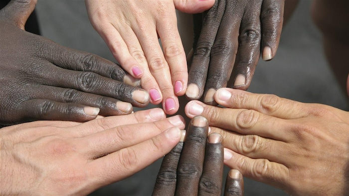 Les mains de différentes couleurs de peau qui se joignent.