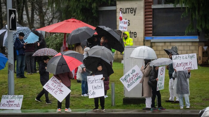 Surrey residents hold signs during a demonstration against extortion-related violence in Surrey, British Columbia, on Monday, Feb., 2, 2026.