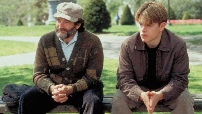 Un homme portant une casquette et une barbe et un jeune homme assis sur un banc dans un parc.