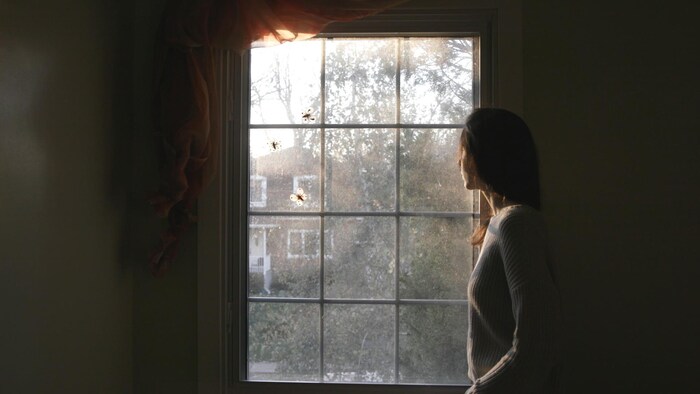 Une femme qui regarde par la fenêtre.