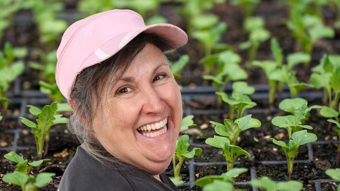 Marthe Laverdière souriante, devant des semis de légumes.