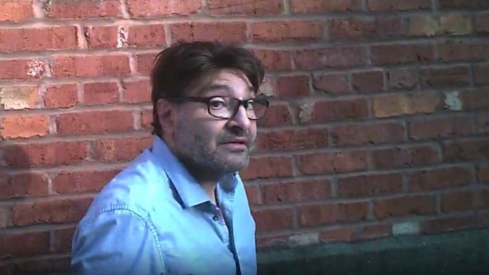 Un homme debout qui regarde le journaliste de Radio-Canada