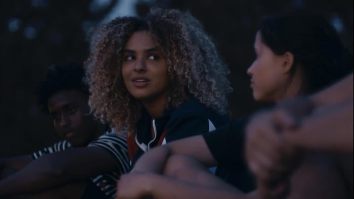 Un groupe de jeunes gens, assis par terre, en train de discuter.