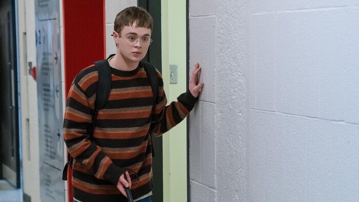 Adolescent dans un corridor avec une canne blanche.