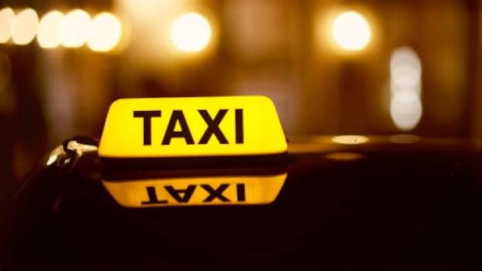 Enseigne d'un taxi illuminée dans la nuit.