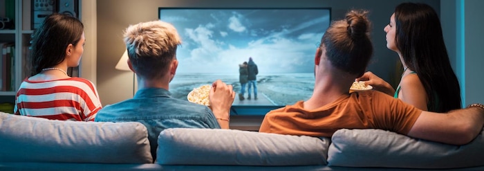 Quatre personnes regardent la télévision sur un divan.