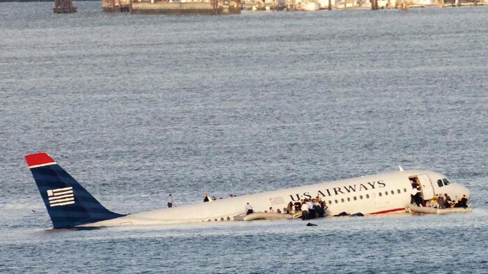 Un avion dans une rivière. Les passagers essaient d'en sortir. 
