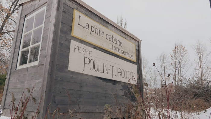 Un kiosque en bois sur lequel on peut lire « La p'tite cabane libre-service, Ferme Poulin-Turcotte ».