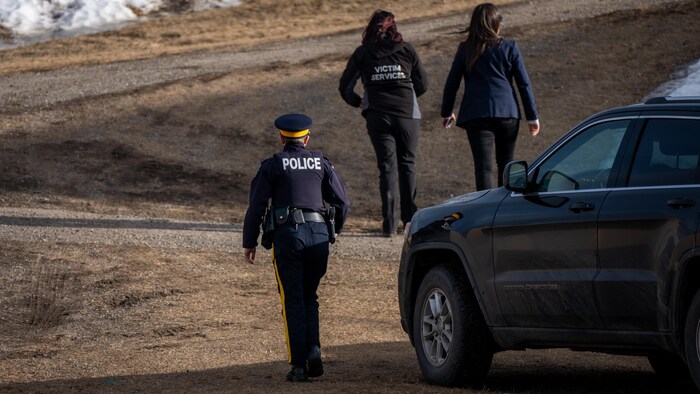 Une agente de la GRC, une membre de l'équipe de soutien aux victimes et une autre femme près de l'école secondaire à Tumbler Ridge.