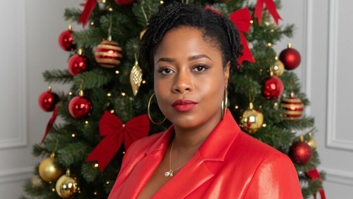 Déborah St-Victor prend la pose devant la caméra devant un sapin de Noël.