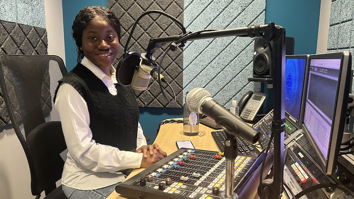 Espérance est assise devant une console de radio.