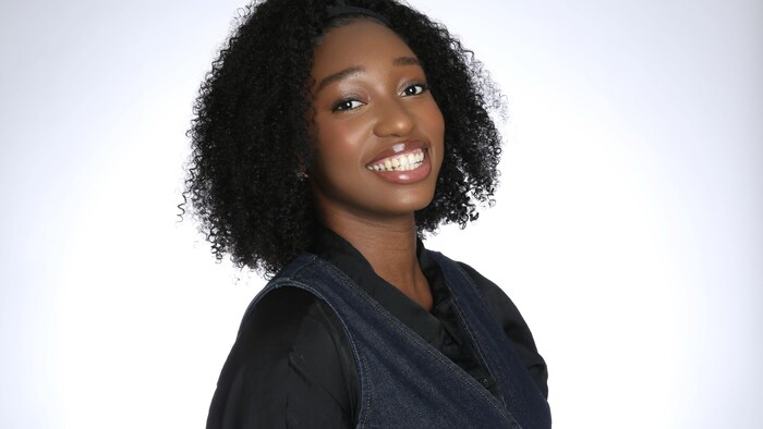 Orphée Moussongo sourit à la caméra devant un fond blanc.