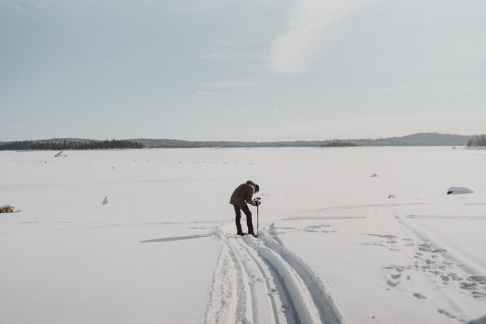 Un homme seul au milieu du lac gelé en hiver.