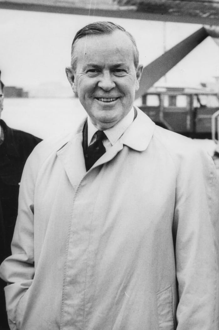 Lester B. Pearson stands smiling next to an airplane. 
