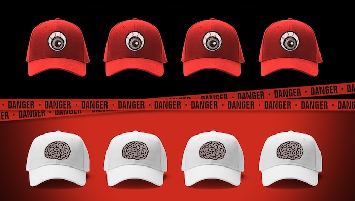 Une rangée de casquettes blanches séparées d’une rangée de casquettes rouges par un ruban où apparaît le mot « danger ».