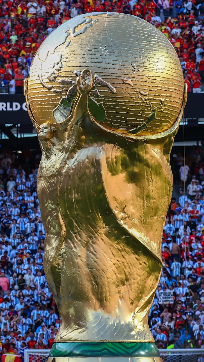 Le trophée de la COupe du monde devant les gradins combles.