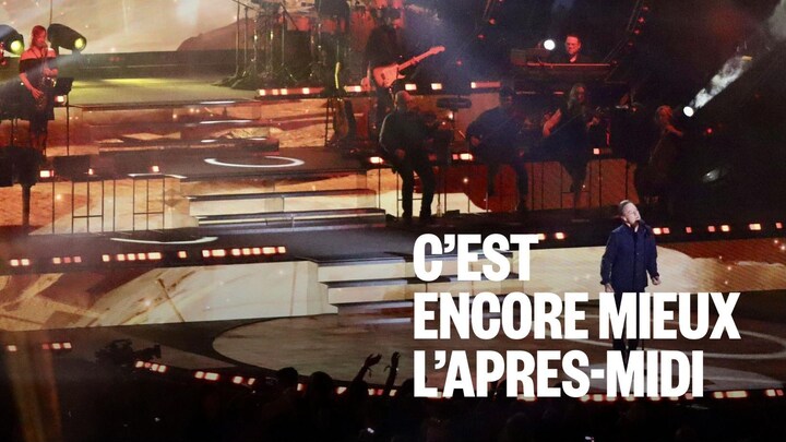 Un chanteur est au-devant de la scène. De nombreux musiciens l'accompagnent à l'arrière.