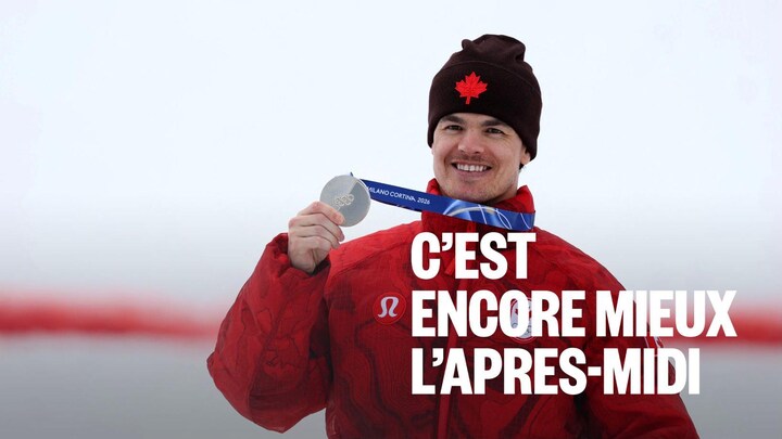 Un athlète sourit en montrant sa médaille d'argent. 