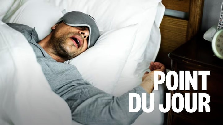 Une personen avec un masque sur les yeux dort avec la bouche ouverte.