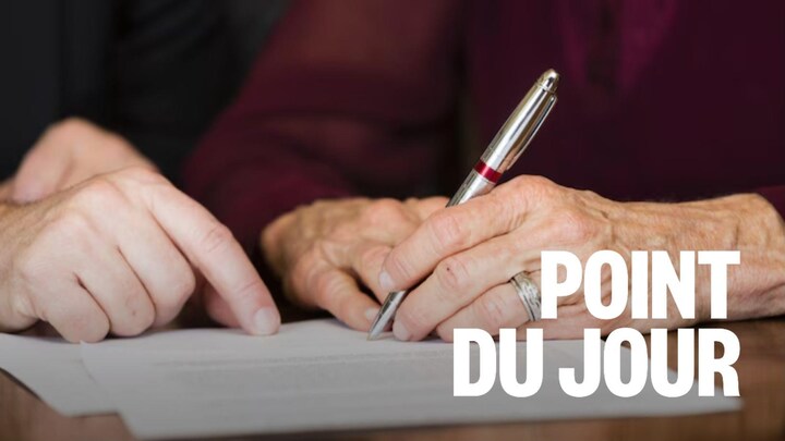 Une personne âgée signe un document.