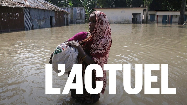 Une femme marche dans les rues inondées de son village.