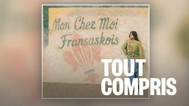 Une jeune femme debout, appuyée contre un mur.