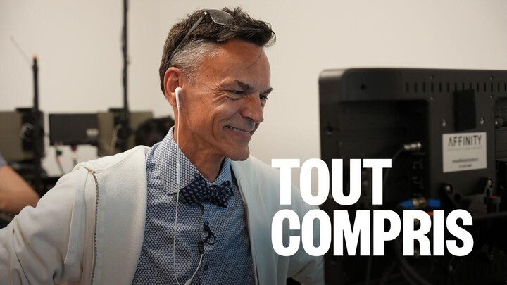 Un homme souriant qui regarde un écran.