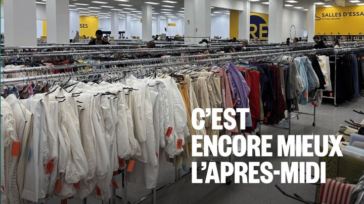 Des rangées de supports à vêtements remplis dans une grande friperie.