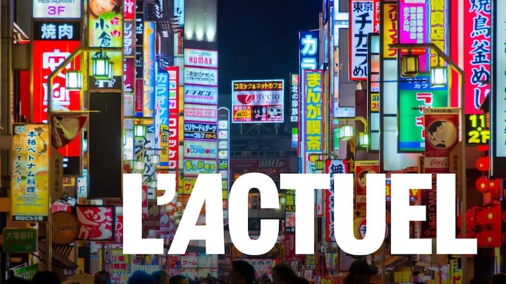 Une foule entourée d'affiches éclairées dans la ville de Tokyo.