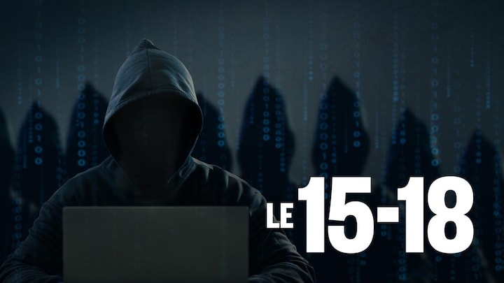 Une personne anonyme et vêtu d'un chandail noir avec une capuche est assise devant un ordinateur.
