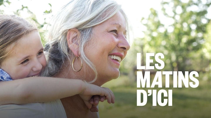 Une femme souriant qui porte une petite fille sur son dos.