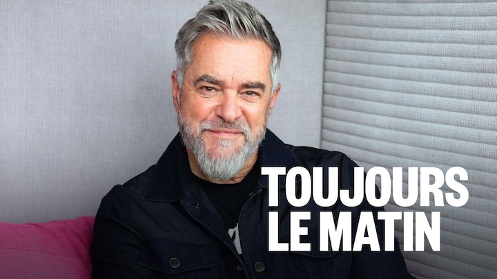 Sylvain Cossette sourit à la caméra, assis dans un fauteuil.