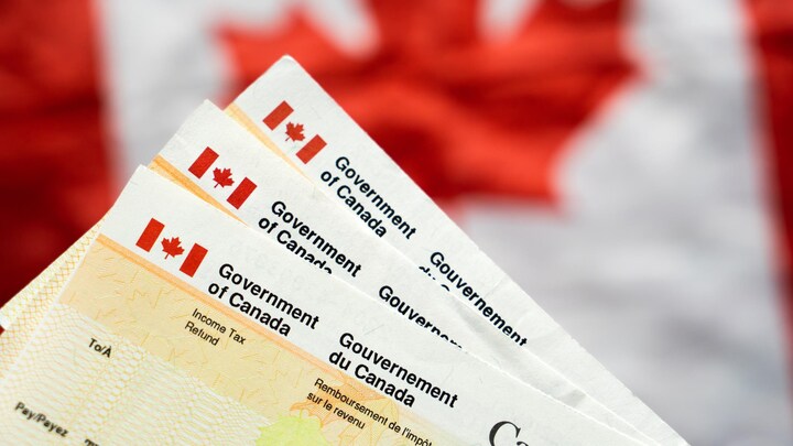 Des documents de remboursement de l'impôt sur le revenu devant un drapeau canadien.