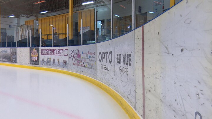 Un coin de la patinoire de Gaspé, avec la bande et des observateurs dans les estrades.