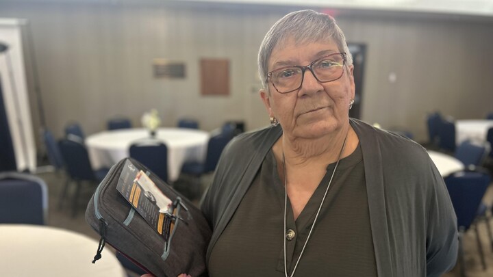Une photo de Norma Dubé avec des documents dans ses mains.