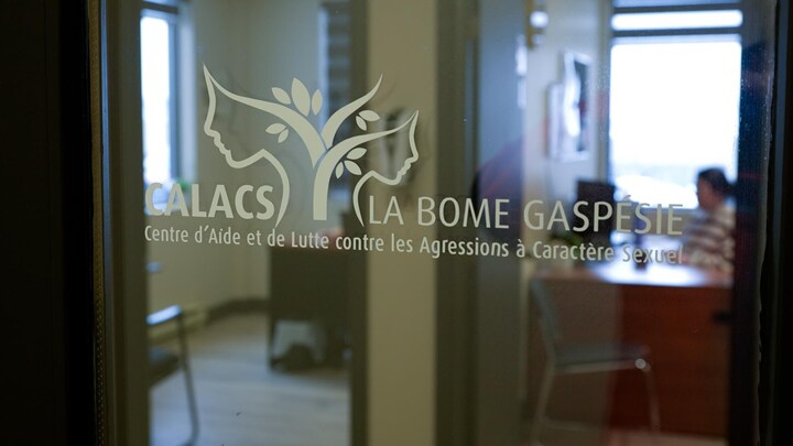 Le nom d'un organisme est écrit sur la porte vitrée d'un bureau.