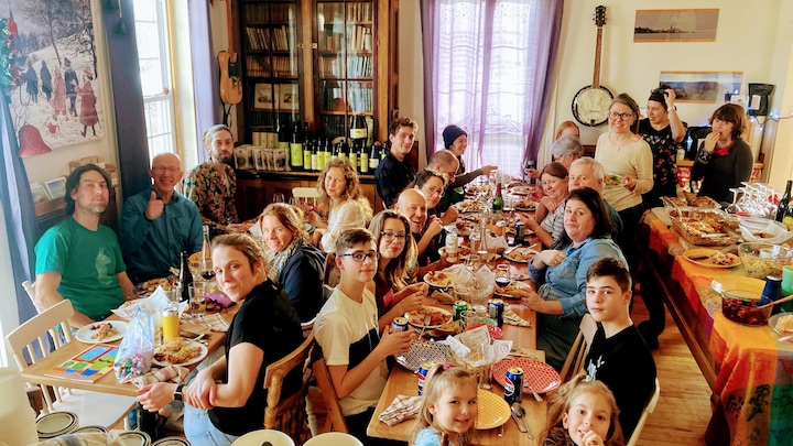 Deux grandes tablées de gens rassemblés autour d'un repas au Noël ensemble 2023.
