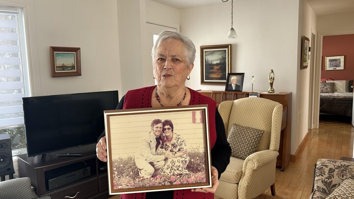 Carmelle Lebreux tient une photo grand format d'elle et son mari plus jeunes.
