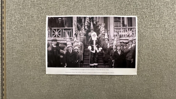 Une photo d'époque met en scène un Père Noël et des enfant qui portent des chapeaux coniques.