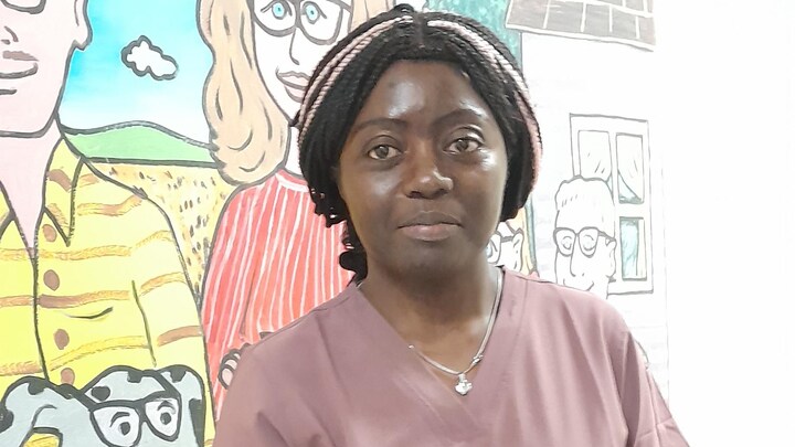 La camerounaise Delphine Mbouche est en tenue de travail devant une fresque.